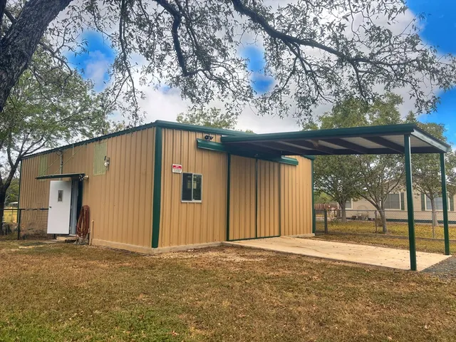 a view of a house with a large tree and wooden fence