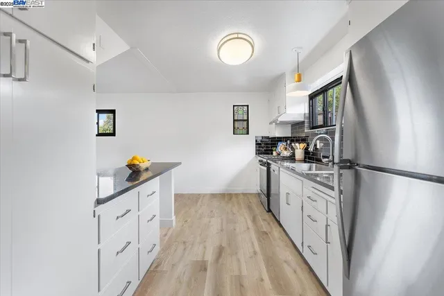 a kitchen with granite countertop white cabinets and refrigerator