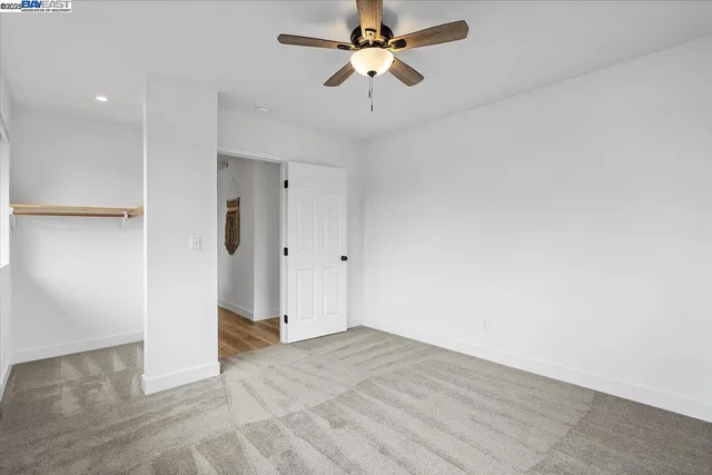 an empty room with a window and a ceiling fan