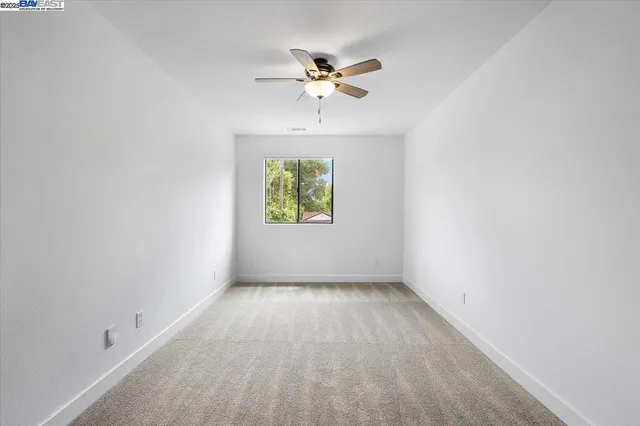 a view of an empty room with a ceiling fan and a window
