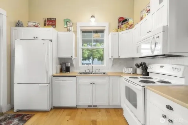 a kitchen with stainless steel appliances granite countertop a sink a stove a refrigerator a cabinets and wooden floor