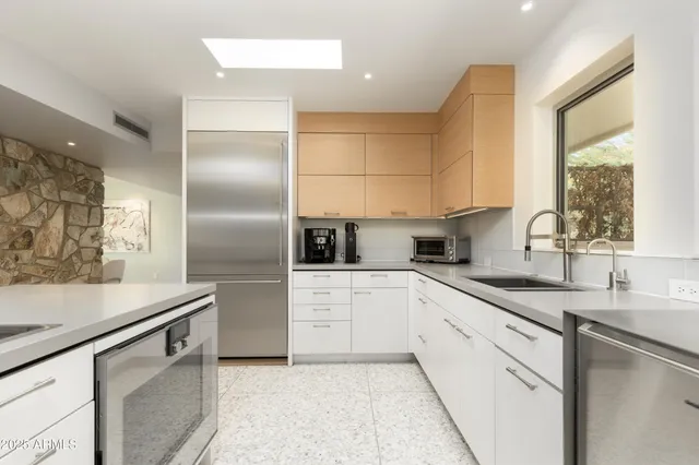 a kitchen with stainless steel appliances granite countertop a sink and a refrigerator