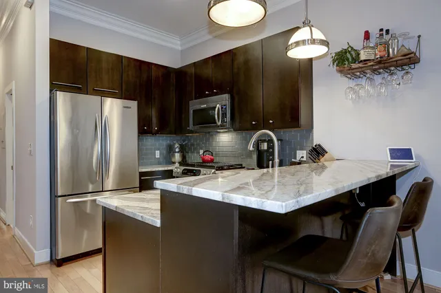 a kitchen with stainless steel appliances a sink cabinets a refrigerator and microwave