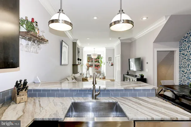 a view of a room with kitchen island stainless steel appliances living room a fireplace and a chandelier