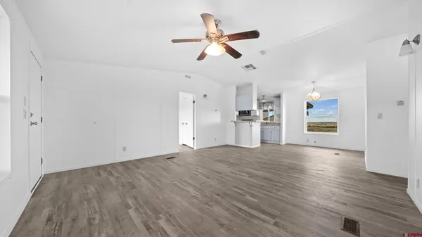 a view of empty room with wooden floor and ceiling fan