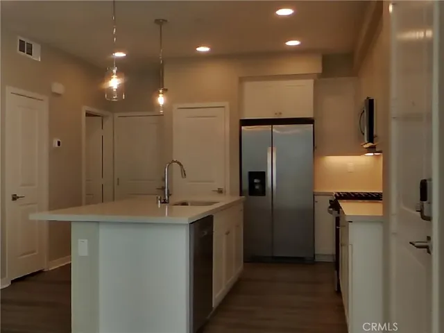 a kitchen with kitchen island a sink stainless steel appliances and cabinets