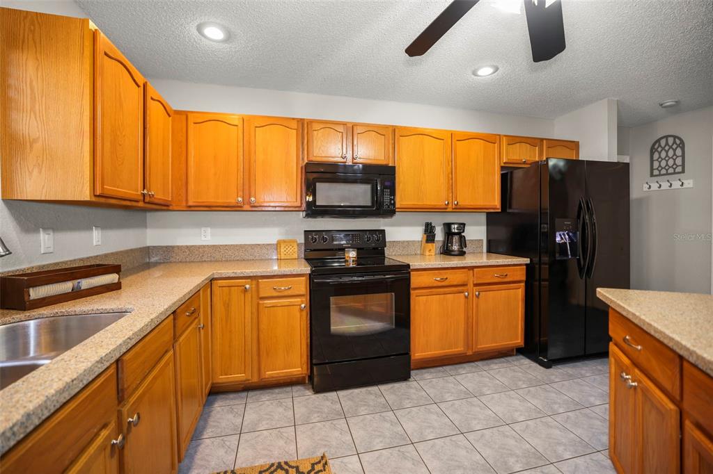 8412 Christopher Lane Weeki Wachee, FL 34613 - Photo 31 of 39 a kitchen with stainless steel appliances granite countertop a refrigerator and a stove top oven
