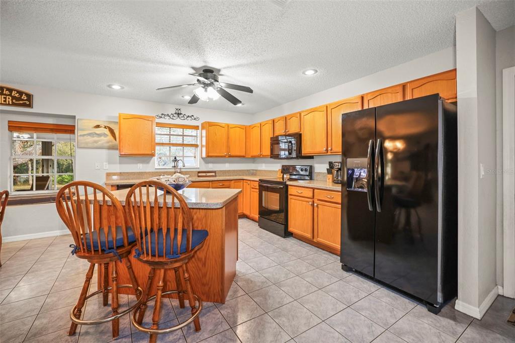 8412 Christopher Lane Weeki Wachee, FL 34613 - Photo 32 of 39 a kitchen with granite countertop a refrigerator a stove a sink and a dining table with wooden floor