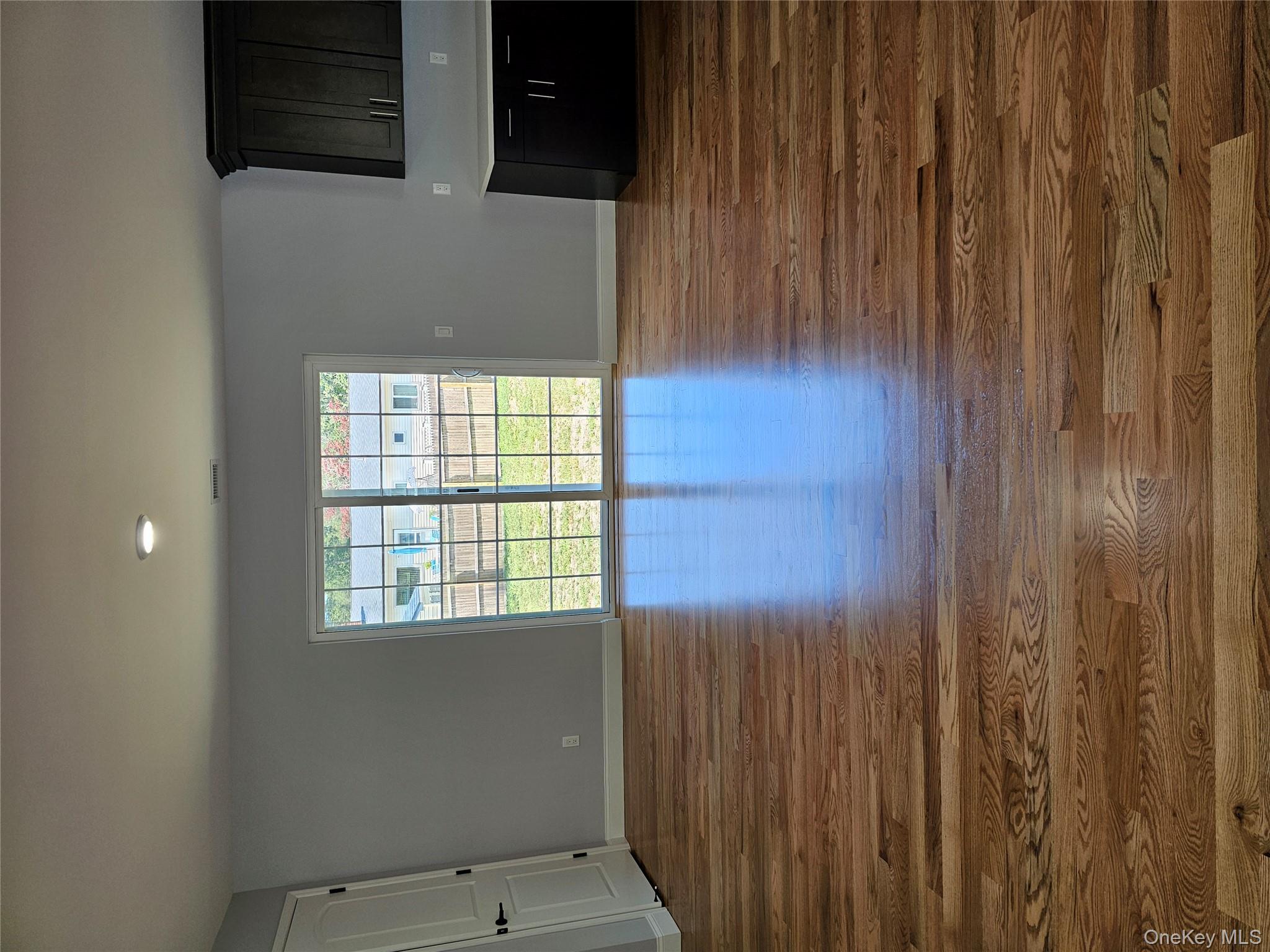 13 North Swezeytown Road Middle Island, NY 11953 - Photo 5 of 9 a view of an empty room with wooden floor and a window