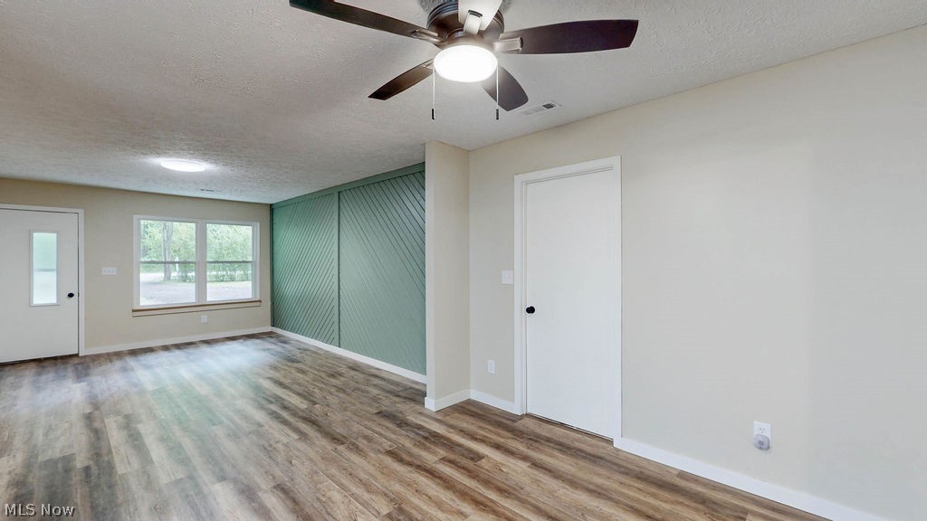 18620 Shaw Road Chagrin Falls, OH 44023 - Photo 17 of 44 Spacious room featuring wood-finish flooring, a contemporary ceiling fan, and a light green accent wall with diagonal paneling