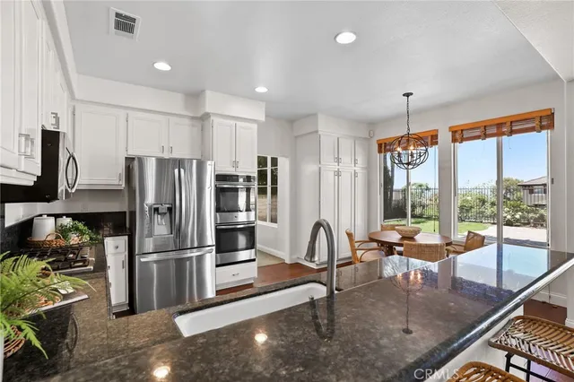 a kitchen with granite countertop white cabinets and stainless steel appliances