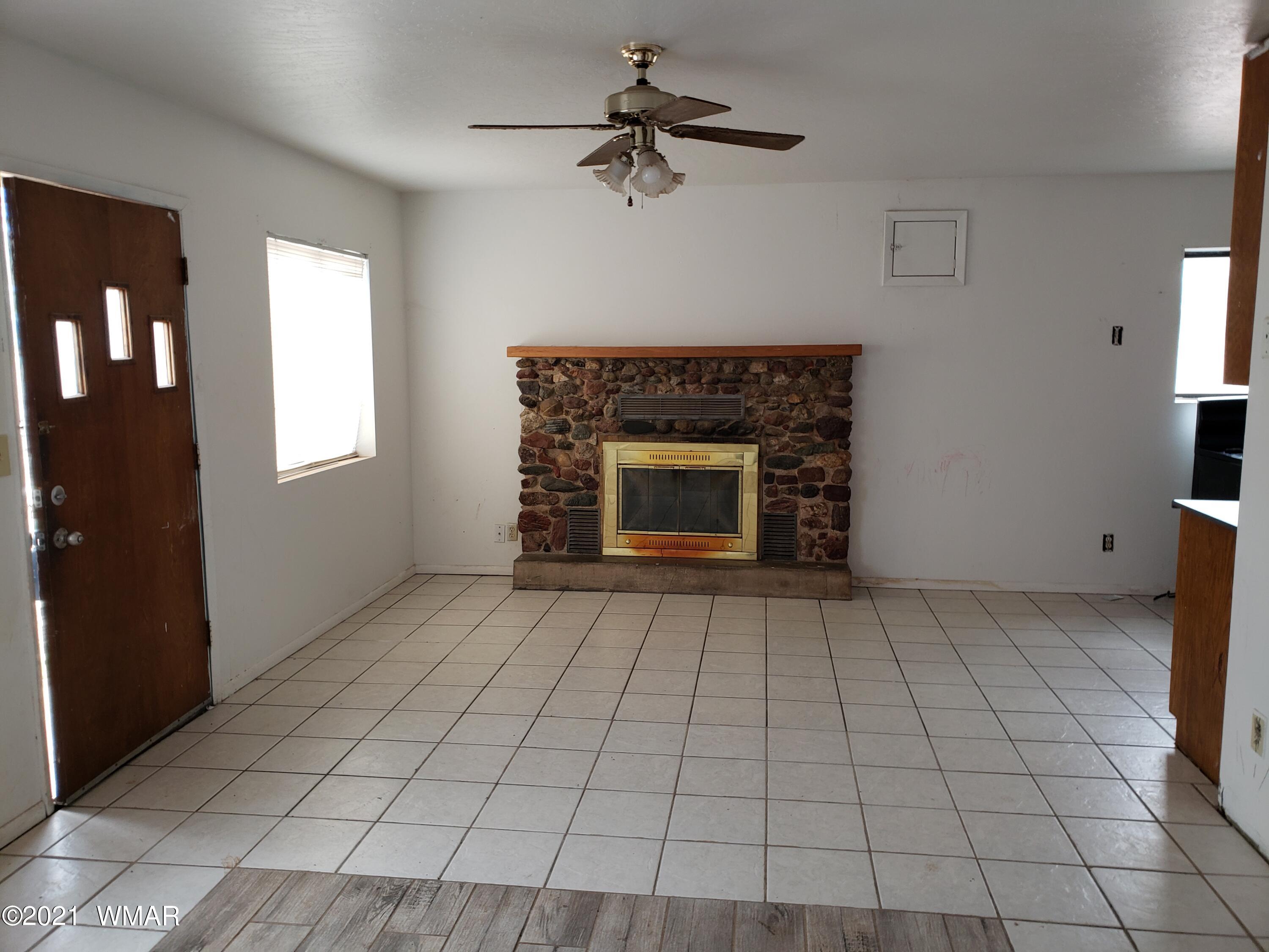 2656 Paper Mill Road Taylor, AZ 85939 - Photo 4 of 14 a view of an empty room with a fireplace and a chandelier fan