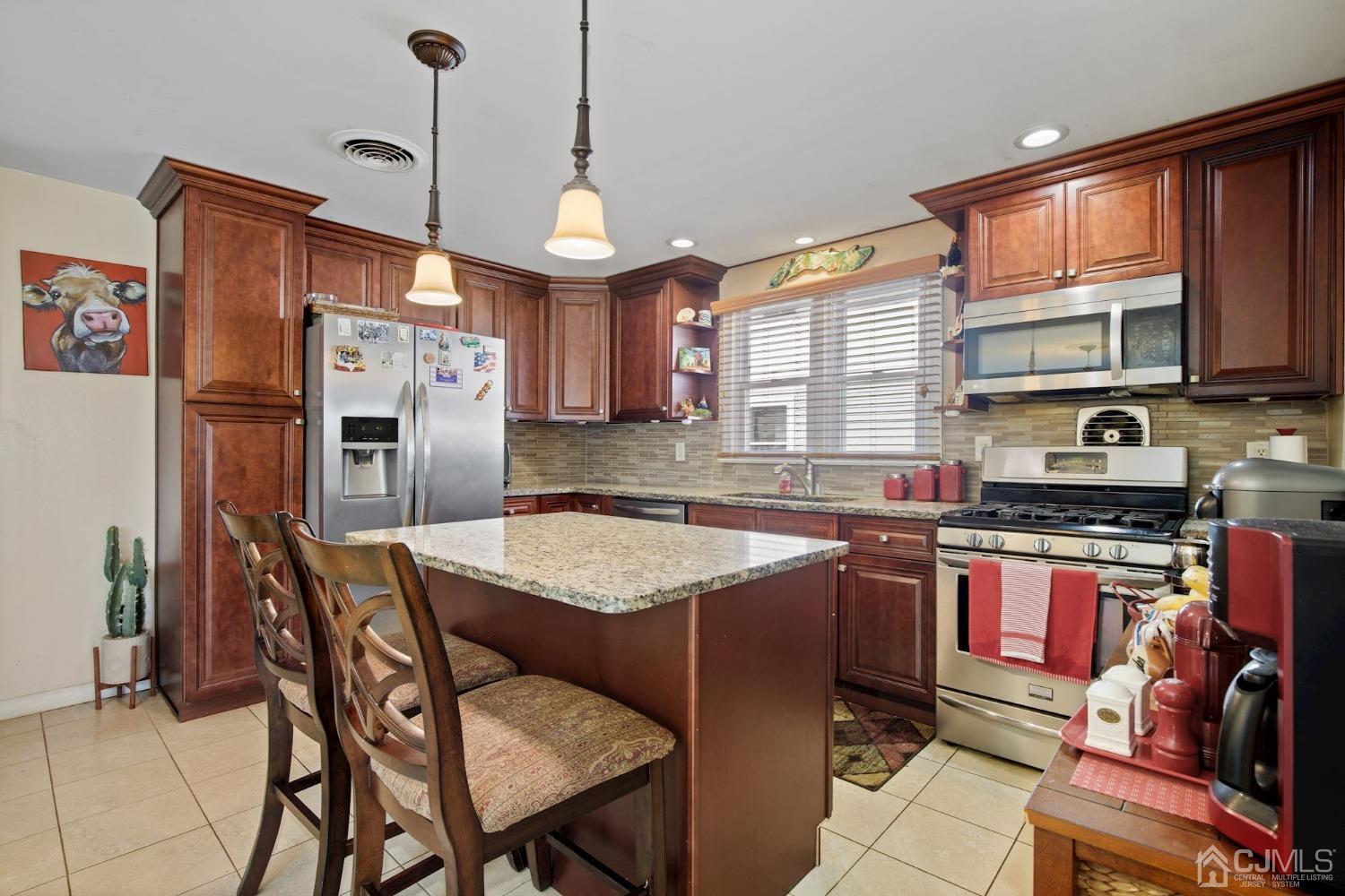 a kitchen with stainless steel appliances granite countertop a sink a stove a refrigerator cabinets and a dining table