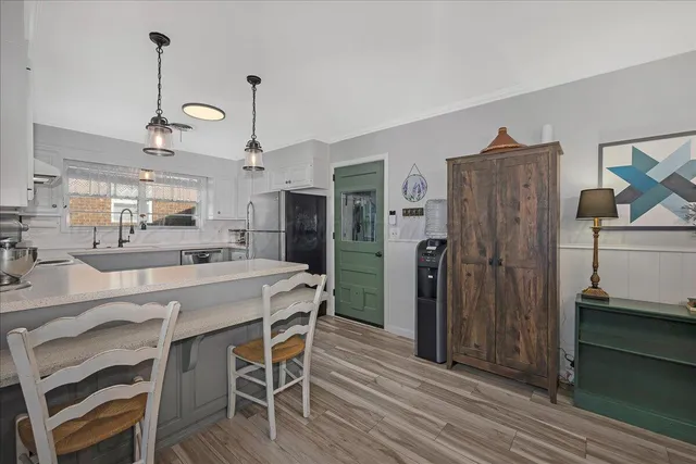 a kitchen with stainless steel appliances granite countertop a refrigerator a microwave oven a stove and a dining table with wooden floor