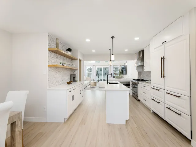 a large white kitchen with lots of counter space wooden floor and stainless steel appliances