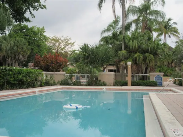 a view of a swimming pool with a lawn chairs and palm trees
