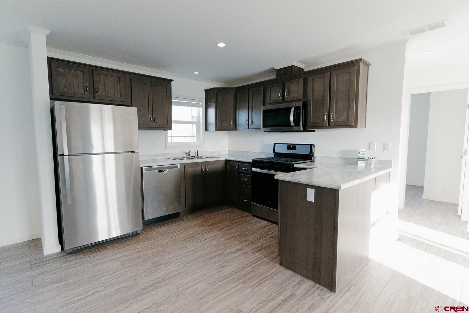 62650 Lasalle Road, Unit 343 Montrose, CO 81403 - Photo 6 of 24 a kitchen with a refrigerator sink and wooden cabinets