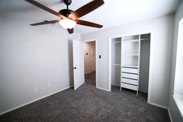 an empty room with closet and a ceiling fan