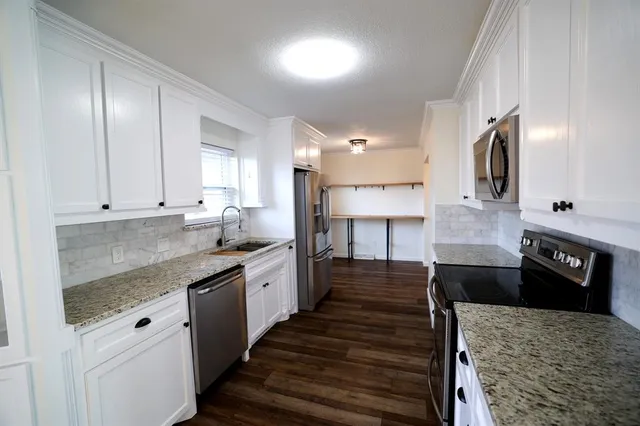 a large kitchen with granite countertop lots of counter space and a sink