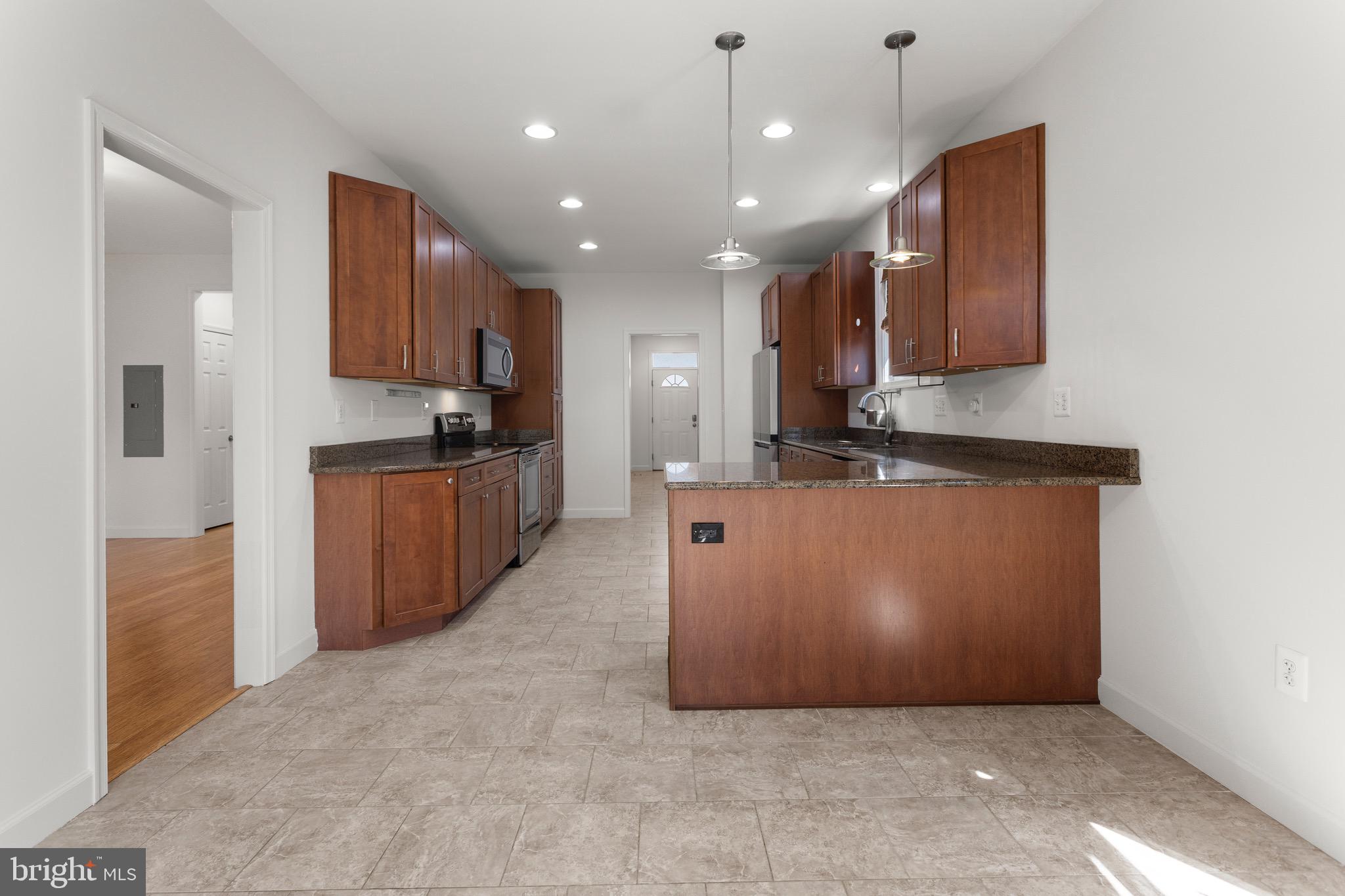 4005 7th Street North Beach, MD 20714 - Photo 13 of 47 a view of a kitchen with kitchen island stainless steel appliances wooden cabinets and a counter top space