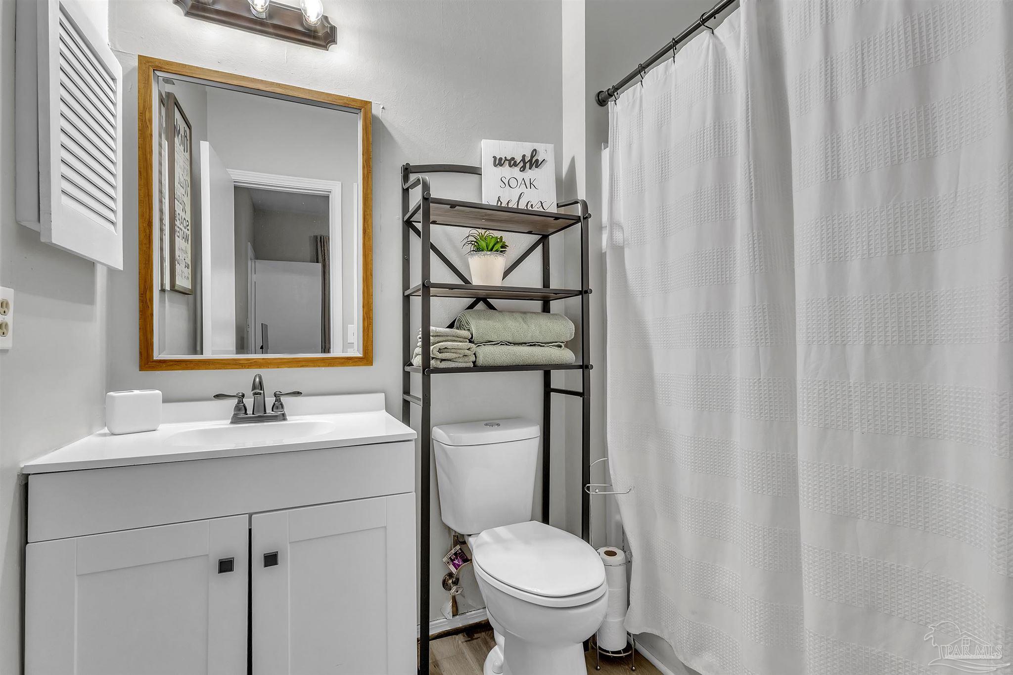 501 East Burgess Road, Unit F5 Pensacola, FL 32504 - Photo 10 of 12 a bathroom with a toilet sink vanity and mirror