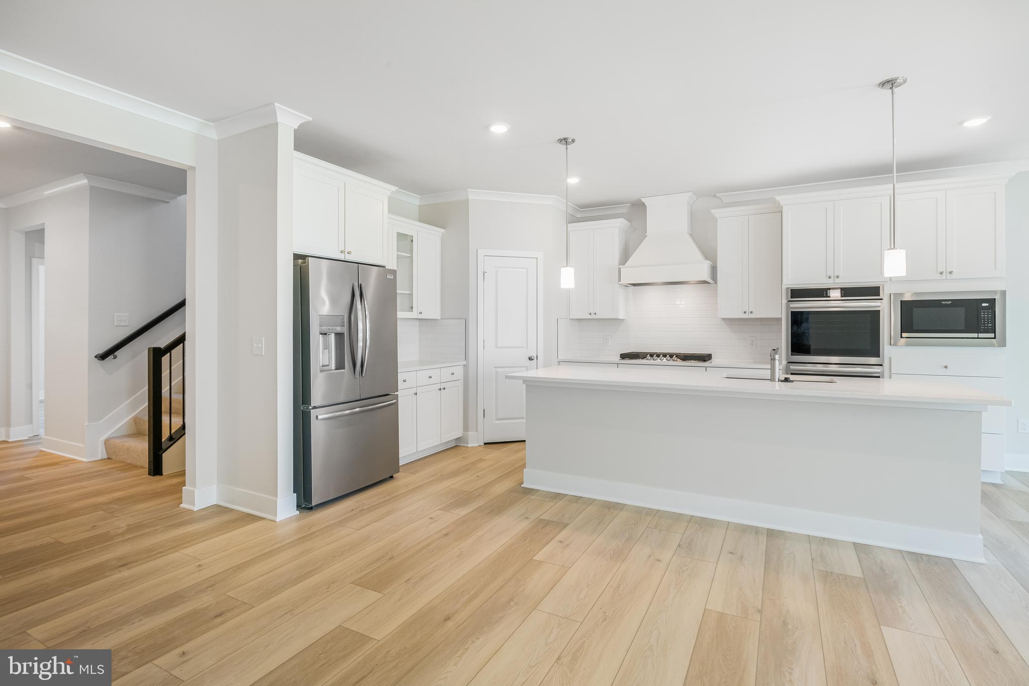 201 Mariners Circle Milton, DE 19968 - Photo 13 of 39 a kitchen with stainless steel appliances kitchen island granite countertop a refrigerator a stove and white cabinets with wooden floor