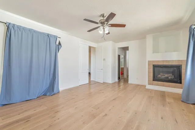 a view of a livingroom with a ceiling fan a fireplace and wooden floor