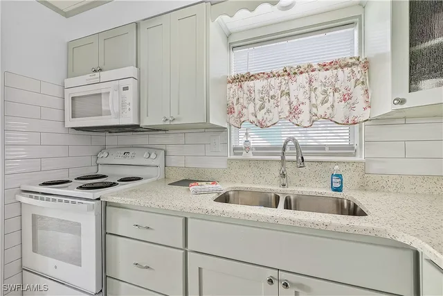 a kitchen with white cabinets and sink