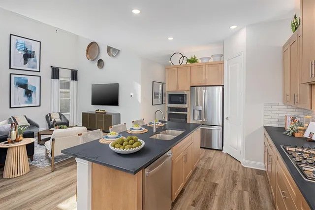 a kitchen with stainless steel appliances granite countertop a sink stove and refrigerator with wooden floor