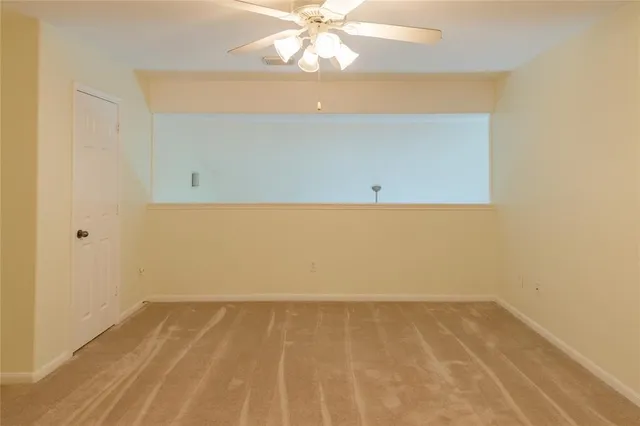 an empty room with a ceiling fan and carpet