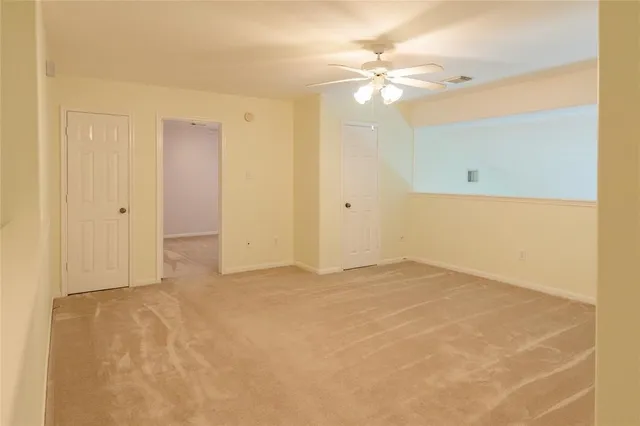 a view of an empty room with a chandelier fan