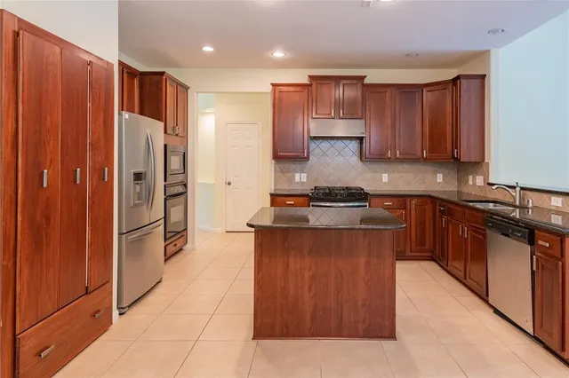 a kitchen with stainless steel appliances granite countertop a refrigerator and a stove top oven
