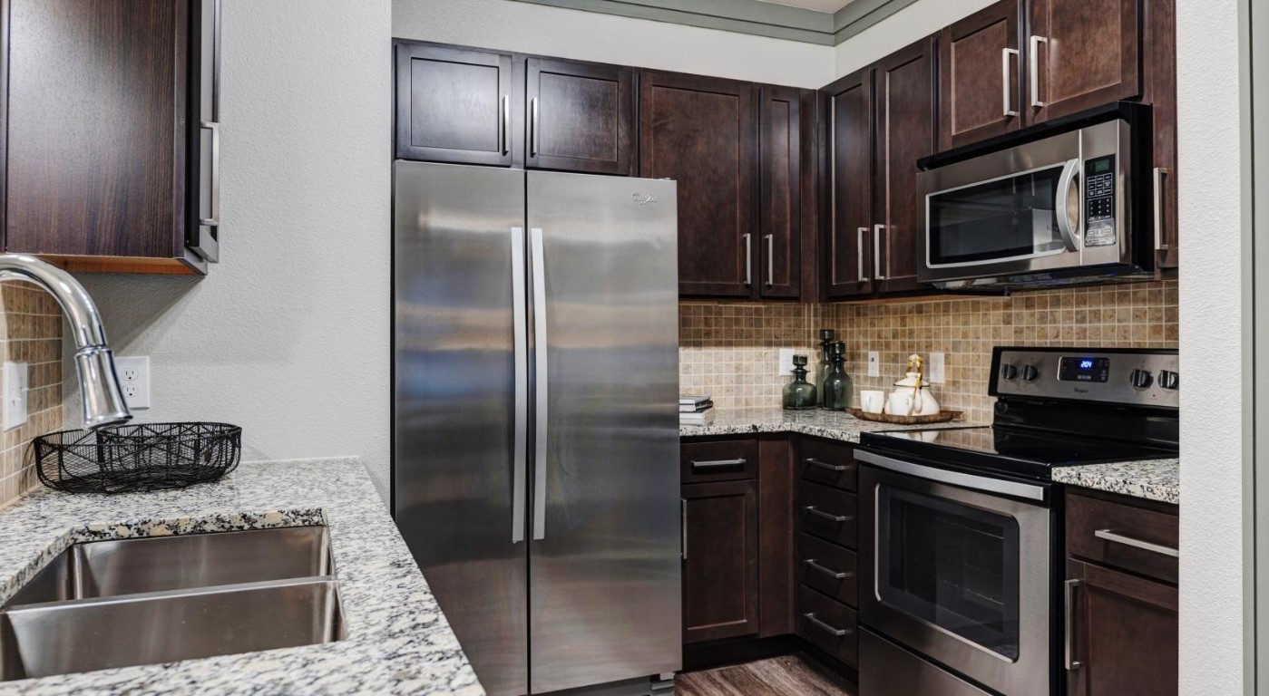 a kitchen with stainless steel appliances granite countertop a stove microwave and refrigerator
