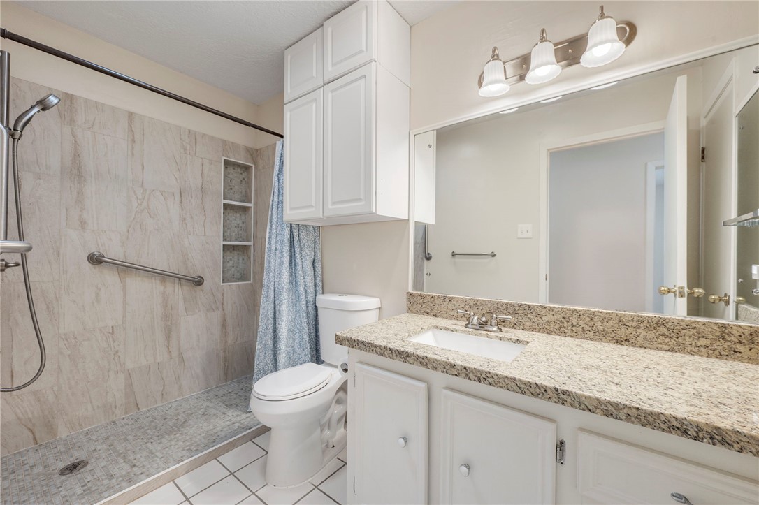2810 Hillside Drive Bryan, TX 77802 - Photo 14 of 22 a bathroom with a granite countertop sink toilet and shower