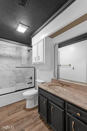 a bathroom with a granite countertop sink a toilet and shower