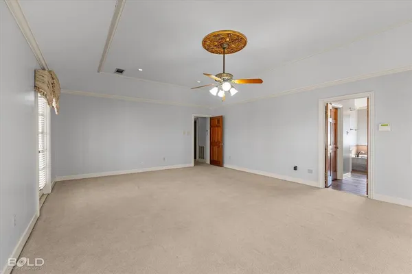an empty room with a chandelier fan and windows