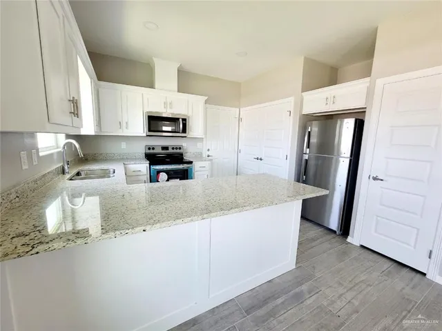 a view of a kitchen with a sink dishwasher a kitchen island hardwood floor and a window