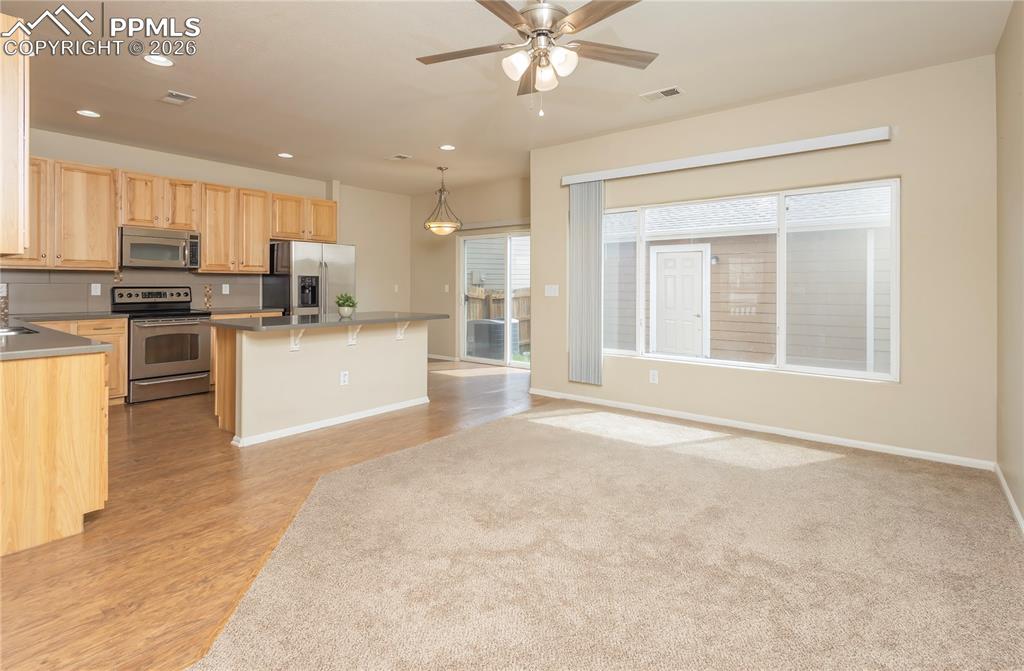 4815 Harrier Ridge Drive Colorado Springs, CO 80916 - Photo 27 of 33 Kitchen with light wood finish cabinets, stainless steel appliances, ceiling fan, and open floor plan