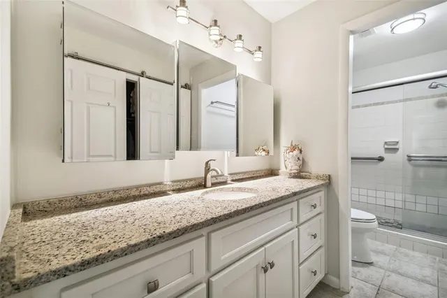 a bathroom with a granite countertop sink two mirror and shower