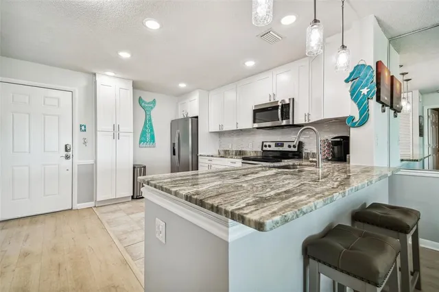 a kitchen with stainless steel appliances granite countertop a stove a sink and a microwave