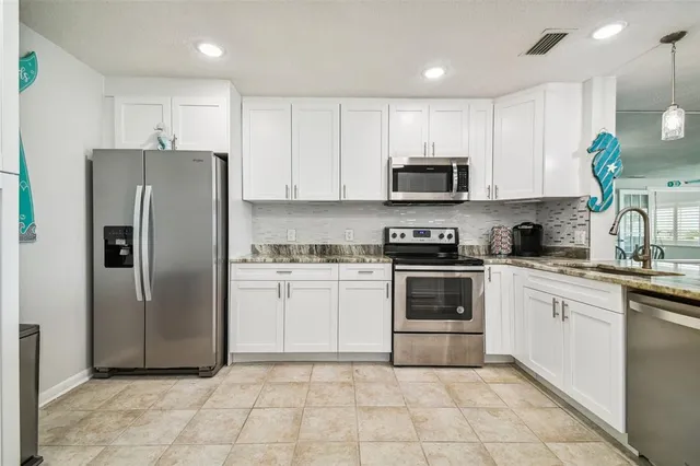 a kitchen with stainless steel appliances granite countertop a stove a sink and a white cabinets
