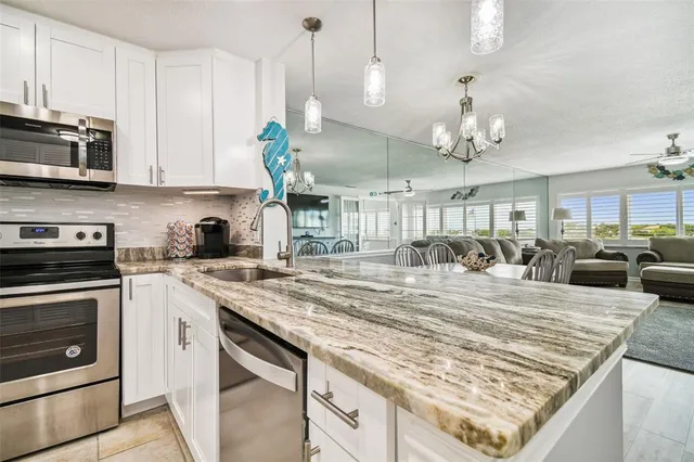 a kitchen with stainless steel appliances granite countertop a sink a stove and cabinets