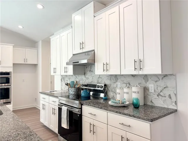 a kitchen with stainless steel appliances granite countertop white cabinets sink and stove
