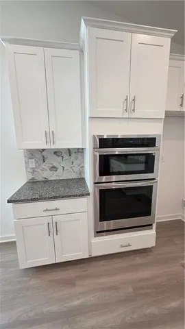 a kitchen with granite countertop a stove and a white cabinet