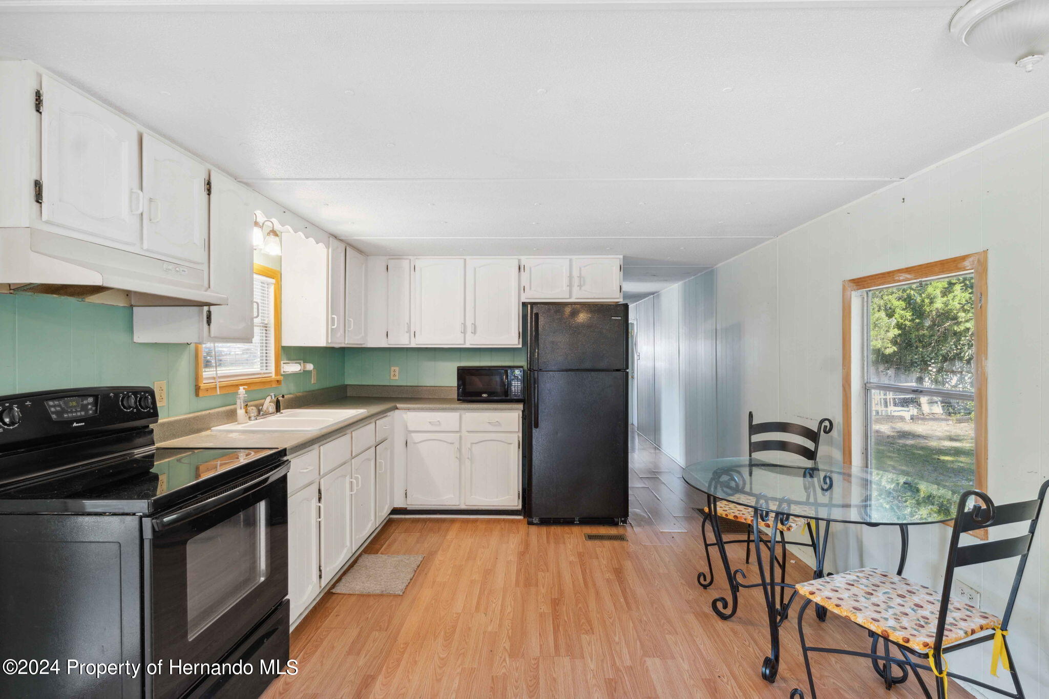10327 East Victory Lane Inverness, FL 34450 - Photo 12 of 35 a kitchen with a refrigerator a stove a sink dishwasher and wooden cabinets with wooden floor