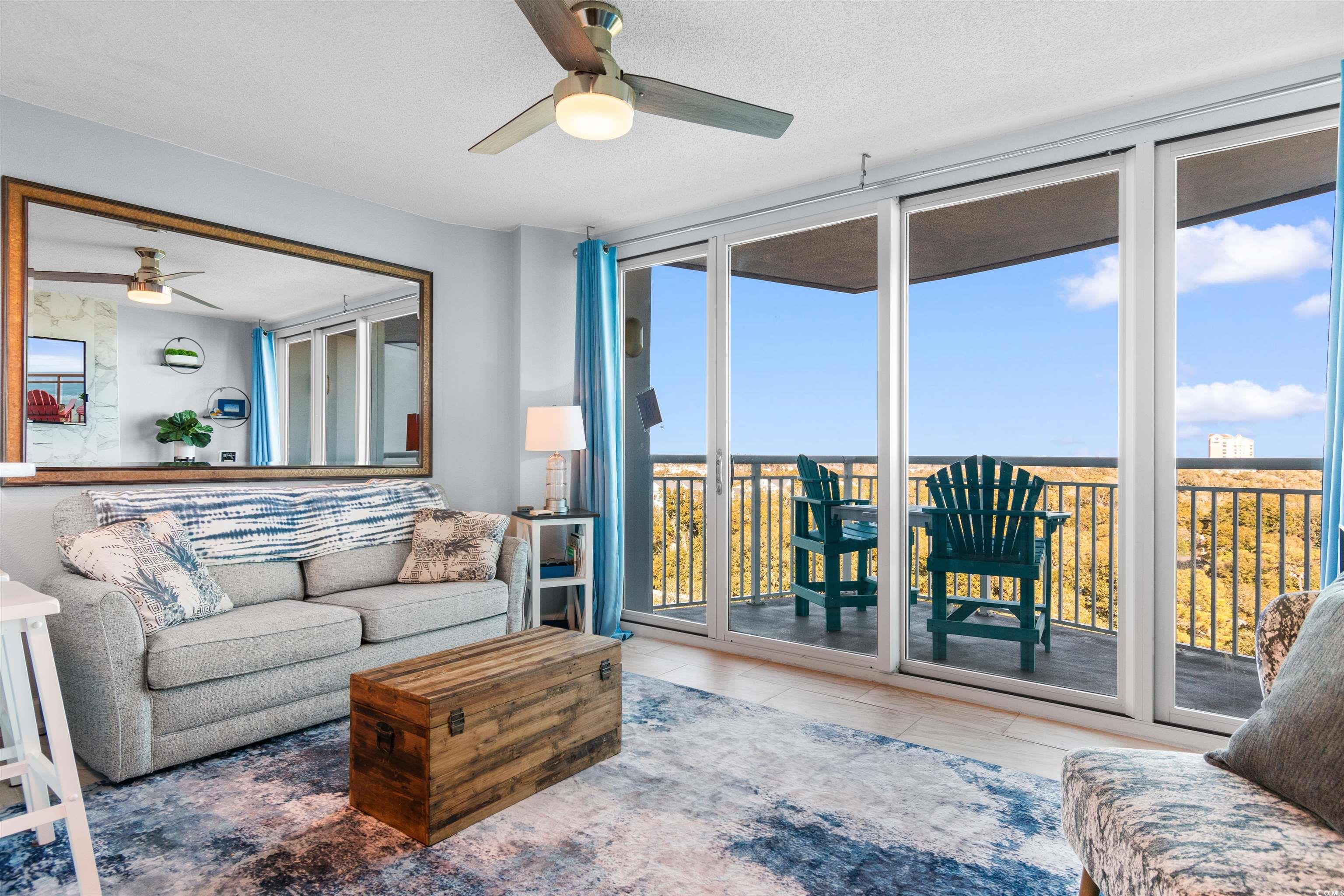 215 77th Avenue North, Unit 603 Myrtle Beach, SC 29572 - Photo 10 of 37 Living room featuring a textured ceiling, ceiling fan, wood finished floors, and expansive windows