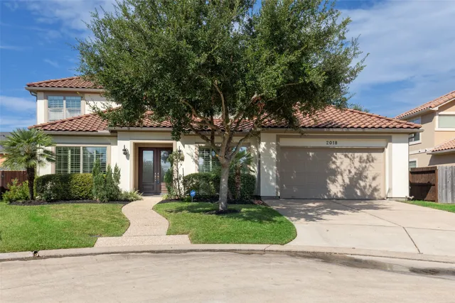 a view of a house with a yard and a large tree