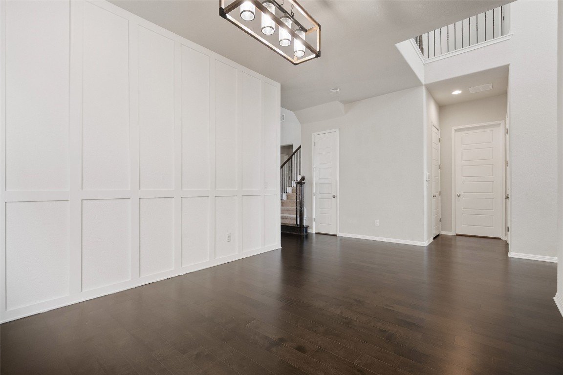 2909 Zelma Drive Cedar Park, TX 78613 - Photo 16 of 40 Unfurnished living room featuring a decorative wall, stairs, dark wood-style flooring, and recessed lighting