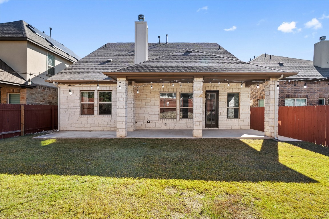 2909 Zelma Drive Cedar Park, TX 78613 - Photo 35 of 40 Rear view of house featuring a chimney, a patio area, roof with shingles, a fenced backyard, and stone siding