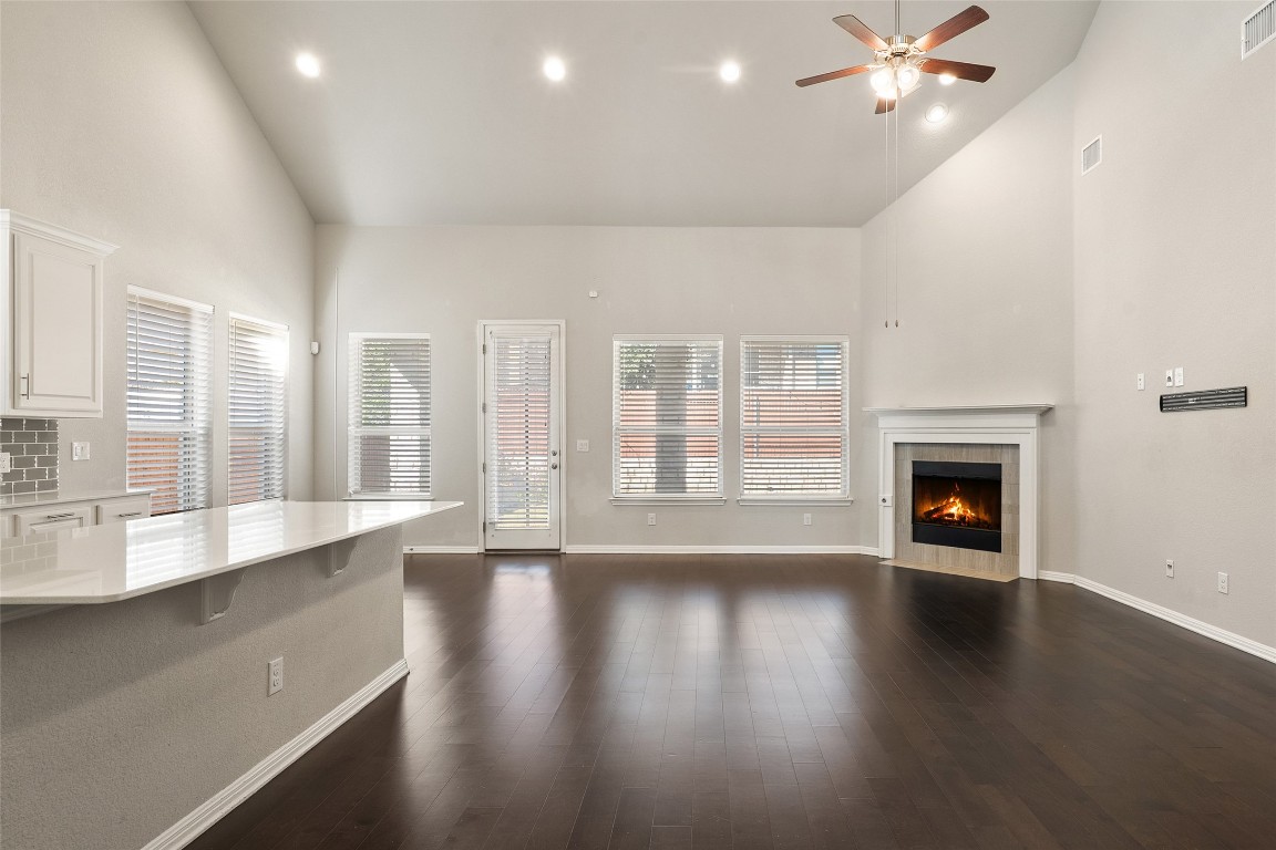 2909 Zelma Drive Cedar Park, TX 78613 - Photo 5 of 40 Unfurnished living room with high vaulted ceiling, dark wood finished floors, a tile fireplace, a ceiling fan, and recessed lighting